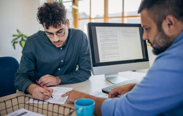 Two people, young man on a job interview in modern office. Male manager is interviewing him.
